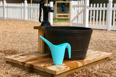 a watering can and a bucket next to a water spigot