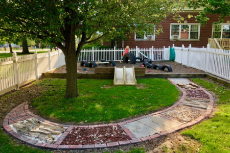 a mulched area with tires and slides behind the grassy area with the sensory path