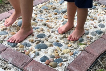 feet on a portion of a path made from pebbles and stones