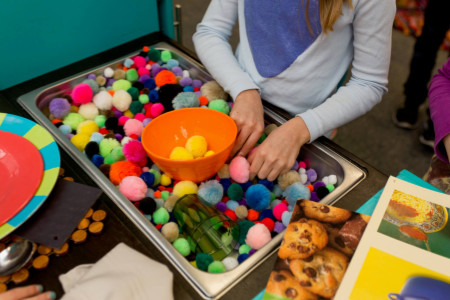 a girl playing in pom poms stored in the sink of the play kitchen