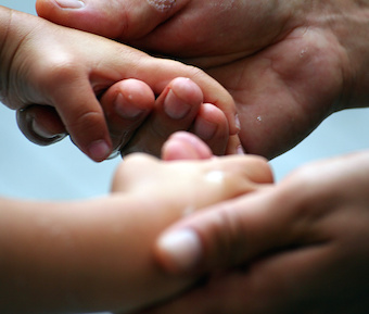 adult holding child's hands